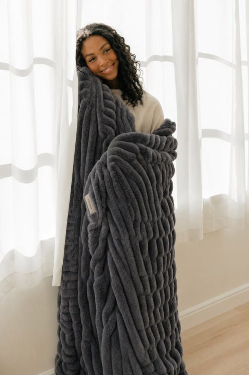Cozella Ribbed Plush Throw in Charcoal wrapped around a woman, full drape